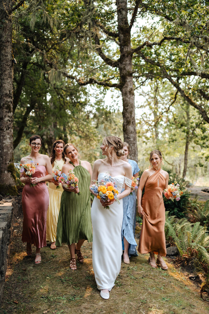 bride and bridesmaids in colorful dresses at wedding 